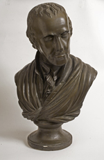 Sculpted bust of wavy-haired white man wearing jacket, cravat, and a cloth draped around his shoulders.