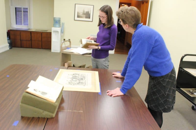 Linda August and Sarah Weatherwax at work laying out exhibition cases. 