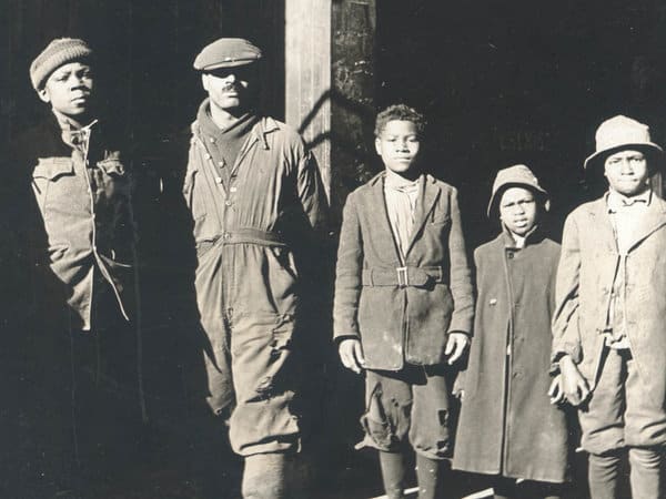 Group of five boys and men stand in a line.