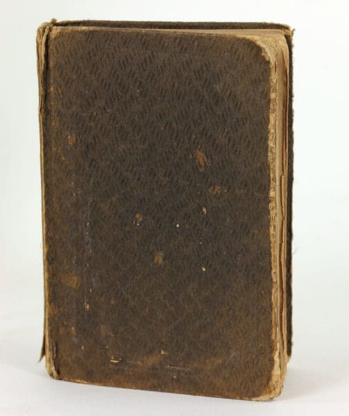 Book with worn cloth bindings, standing upright.