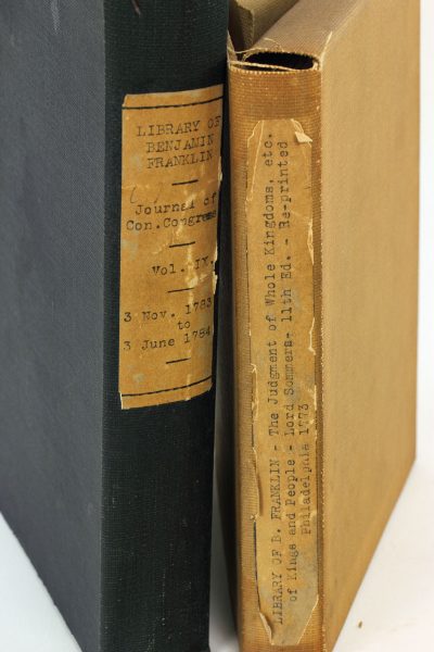 Detail of the cloth book covers of teo books from the library of Benjamin Franklin. The books are standing up, allowing a comparison of their sizes.