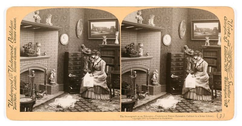 A stereograph showing an affluent middle-class woman using a stereograph viewer in her parlor. Title: “The Stereograph as an Educator.” Creator: Underwood & Underwood, circa 1901.