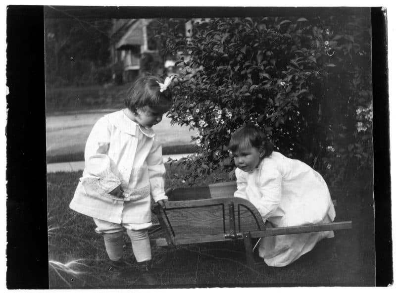 The Morris siblings as babies. The younger wears a long dress while the elder wears a short dress.