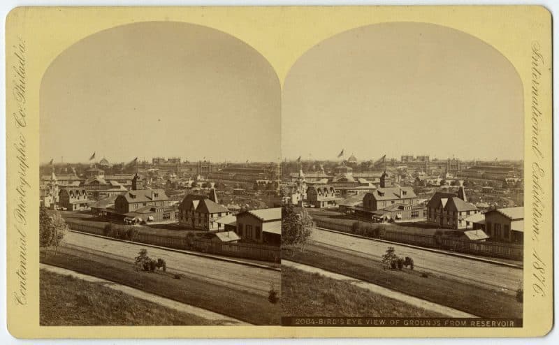 One of the many stereographs produced of the Centennial Exhibition of 1876 showing the grounds in Fairmount Park, Philadelphia. Massive temporary buildings were constructed for the exhibition, including the Main Exhibition Building, Machinery Hall, Horticultural Hall, and the Pennsylvania Railroad Depot. The exhibition celebrated ideals of democratic equality, consumer culture, and technological progress. Title: Bird’s Eye View of Grounds from Reservoir. Creator: Centennial Photographic Co., circa 1876.
