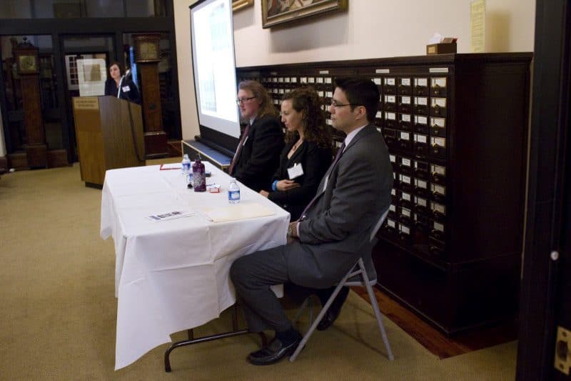 Photograph depicting three panelists at a table.