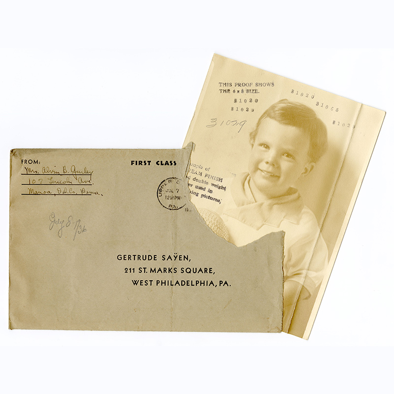 Three-quarter length portrait of white boy toddler, with medium color hair, seated, looking ahead and attired in a romper and holding a ball. Stamped texts cover the photograph. 
