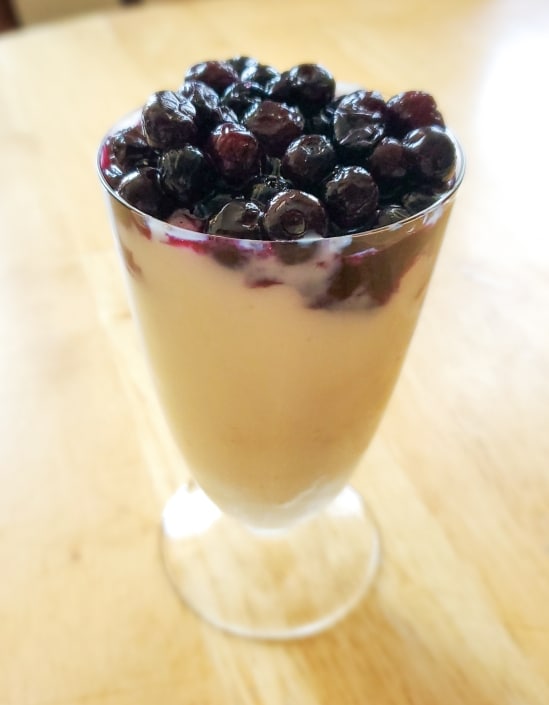 Pudding topped with blueberries in serving glass.