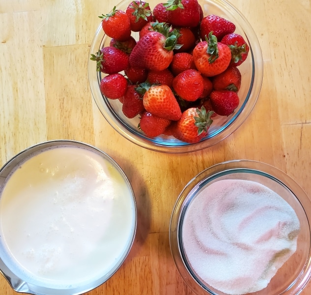 Strawberries, cream, and sugar each in their own bowls.