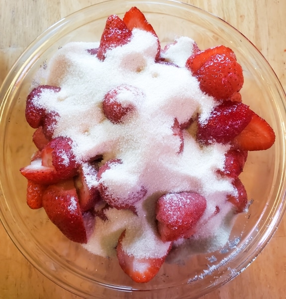 Strawberries and sugar in a glass bowl.