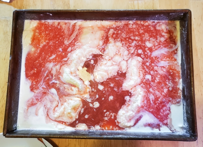 Metal pan filled with unmixed juice and frozen cream.