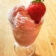 Strawberry ice cream in a glass serving dish with a fresh strawberry.