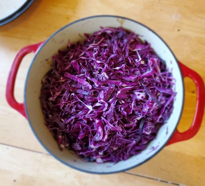 Shredded red cabbage layered with salt in a crock pot