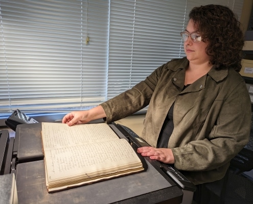 Photograph of Abigail Guidry using the book scanner to digitize a bound volume at the Library Company