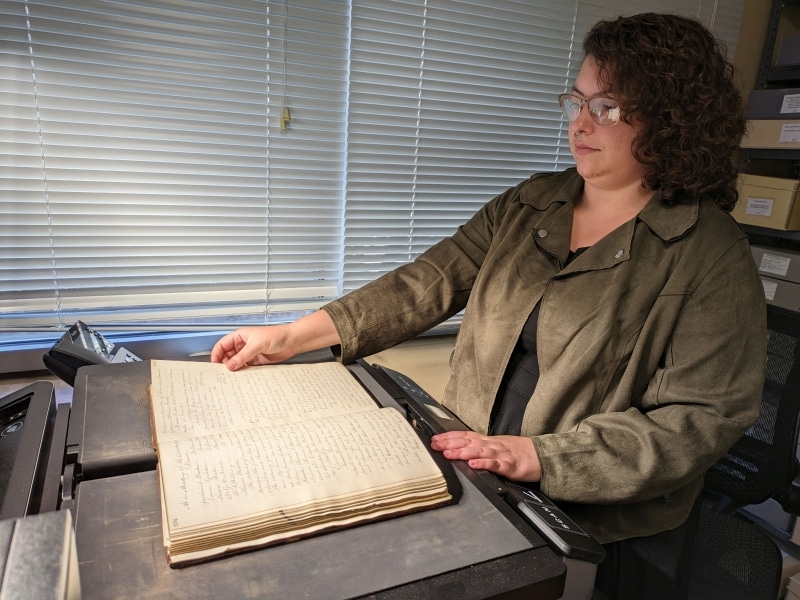 Photograph of Abigail Guidry using the book scanner to digitize a bound volume at the Library Company