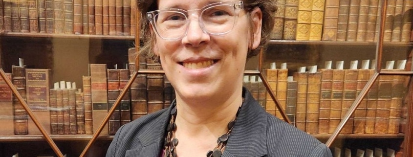 Photograph of Dana Dorman in front of bookcase