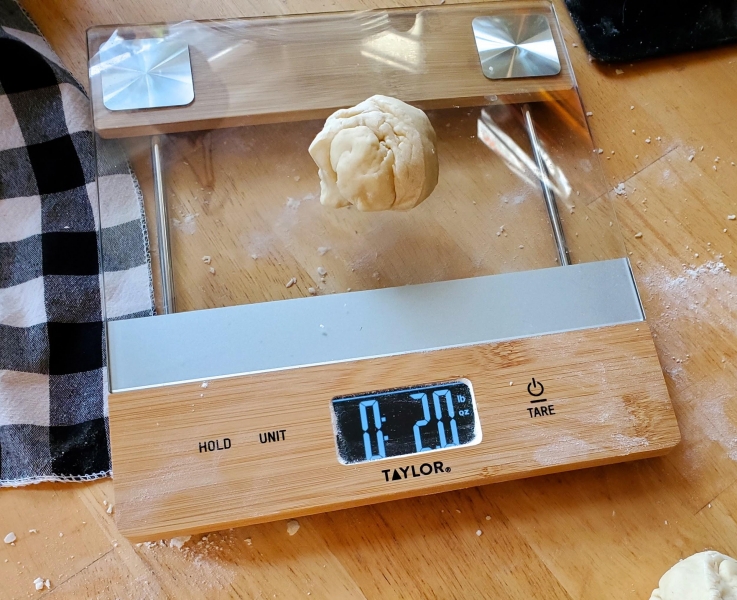Image of one ball of dough on a scale, weighing exactly two ounces.