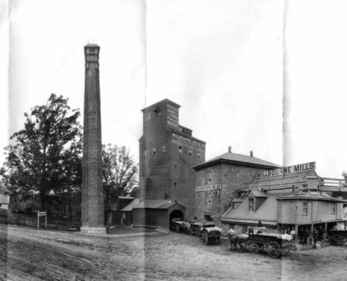 Black and white photograph of exterior of Millbourne Mills in Upper Darby showing horse-drawn wagons lined up outside