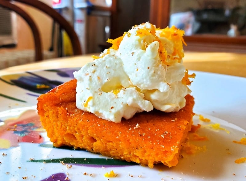 Carrot pudding served with nutmeg, orange zest, and whipped cream