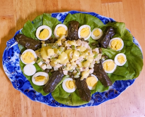 Chicken salad served on a platter with hard boiled eggs and stuffed grape leaves
