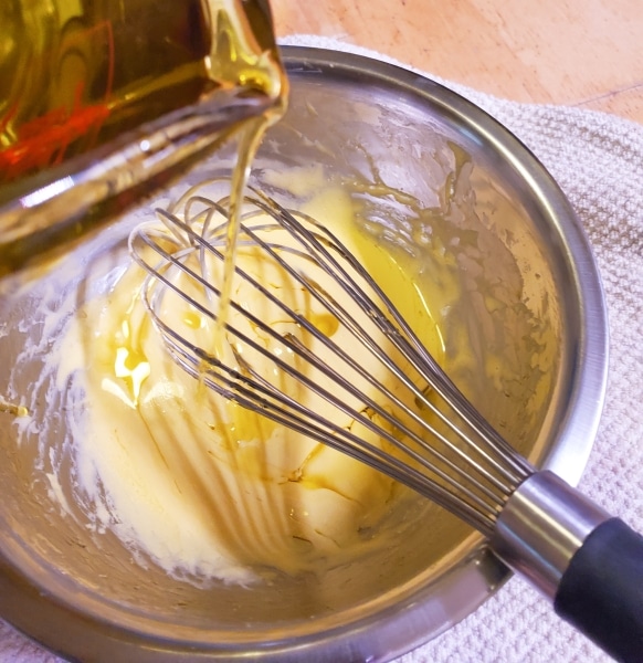 Adding olive oil to egg yolks in a steady stream