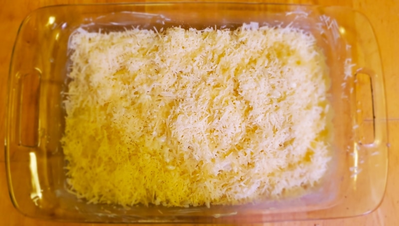 Melted butter added to parmesan topped noodles in a zig-zag fashion